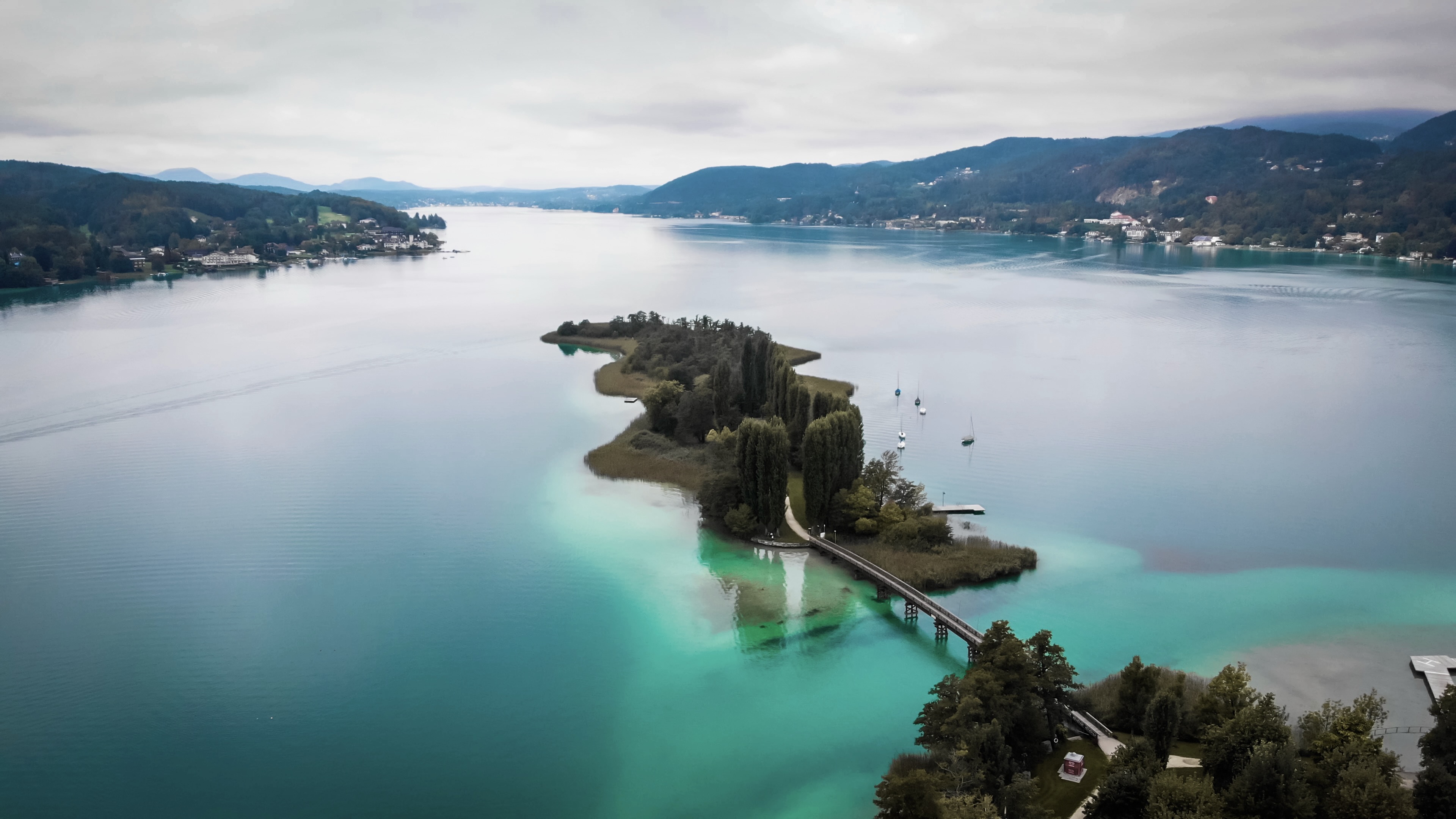 A small island in the clear, turquoise water of a lake in Carinthia