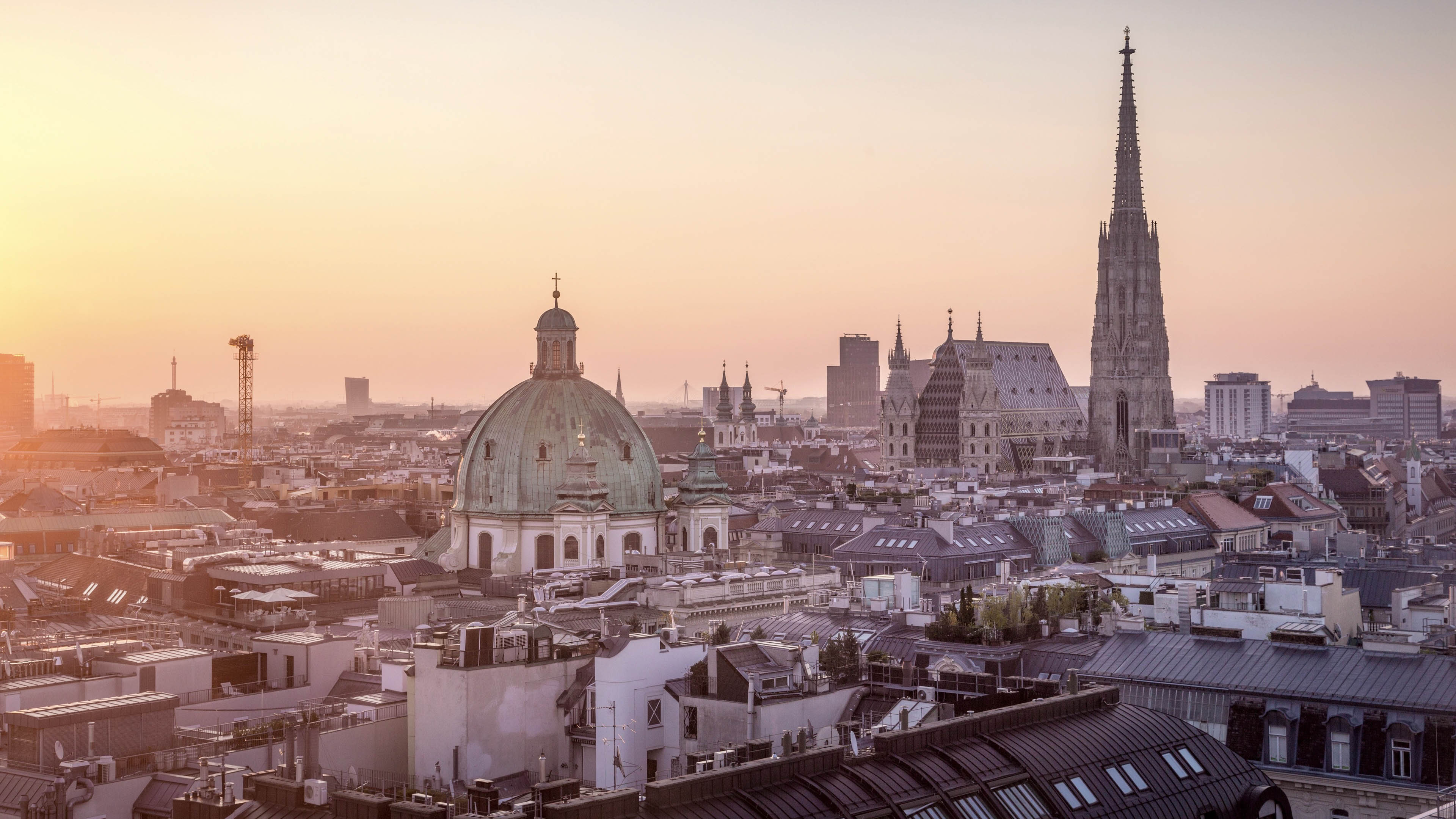 The sun is setting over the rooftops of Vienna, with St. Stepehens Cathedral and Peterskirche