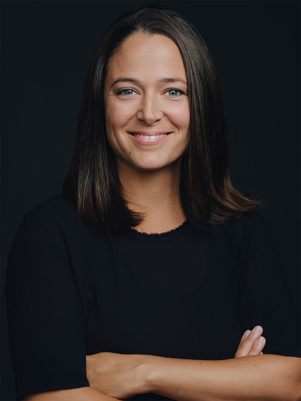 Jenny Newrkla smiles into the camera with her arms crossed.